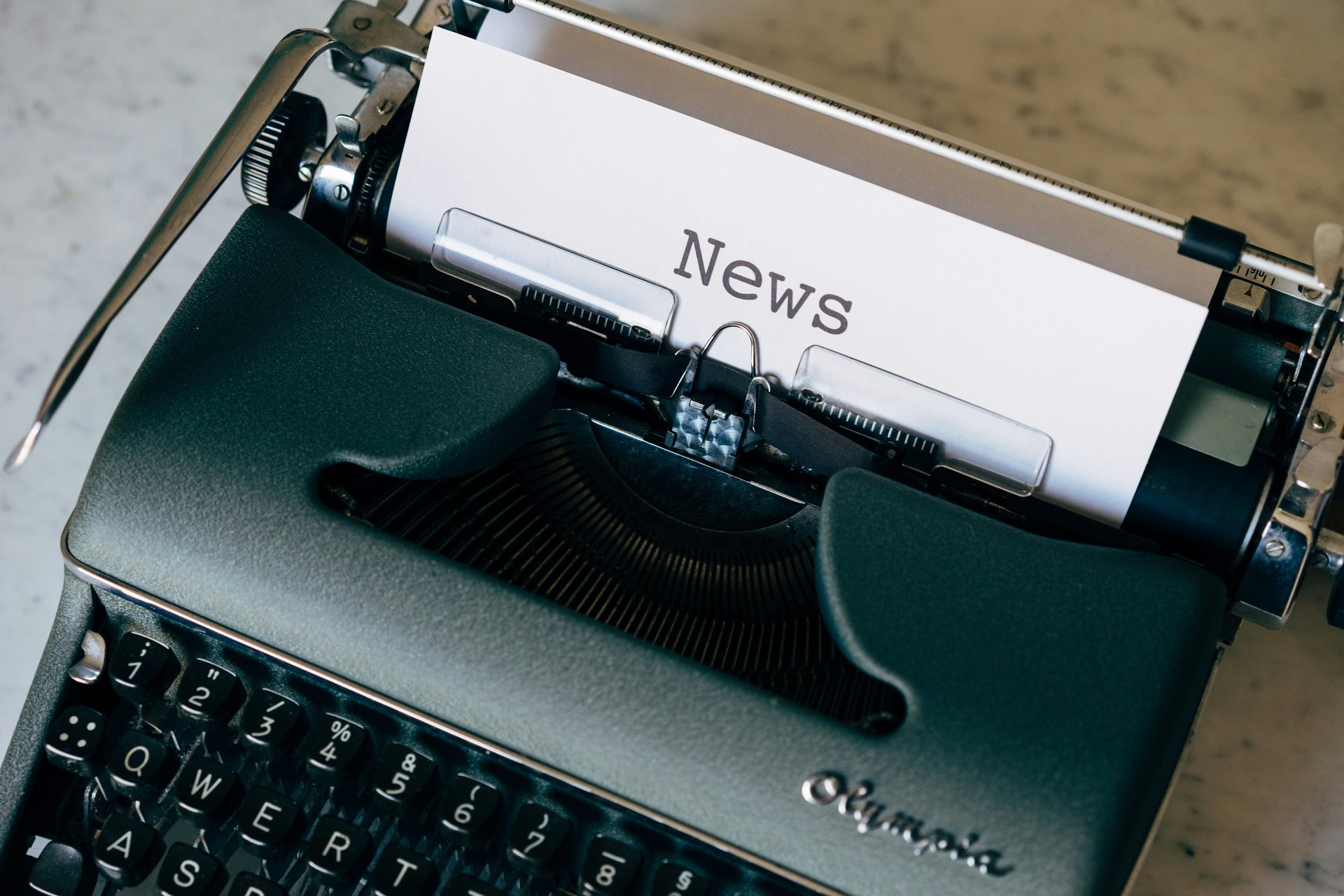 Een typemachine met een vel papier waarop 'News' staat, als symbool voor het schrijven van een nieuwswaardig verhaal.