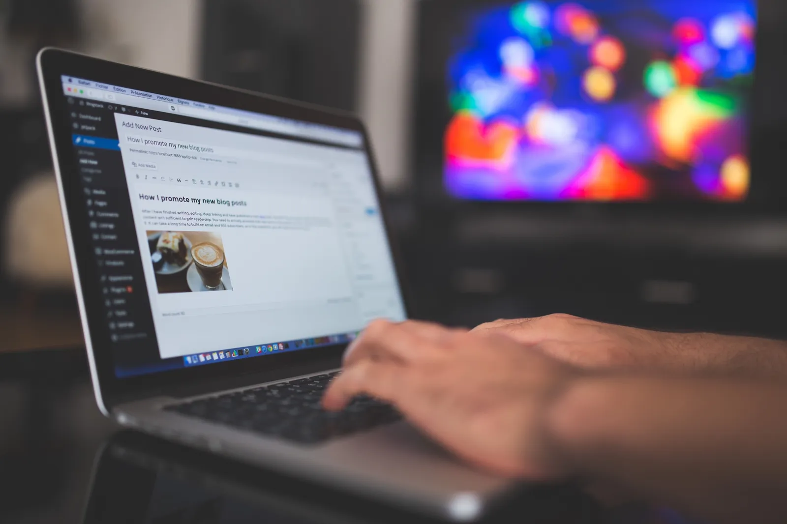 Een laptop met een blogpost in een editor, de handen aan het typen